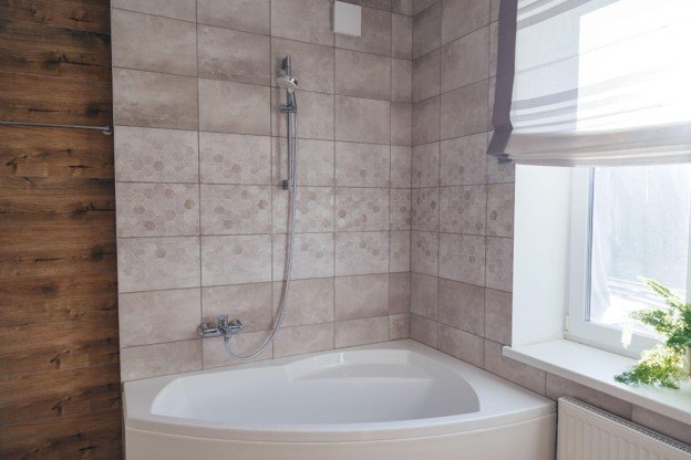 Finished bathtub and shower installation with tiled surround, modern shower fixture, and updated bathroom finishes.