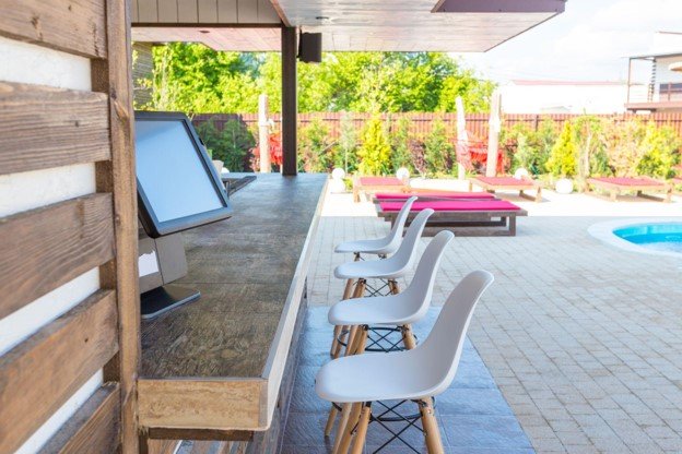 Finished outdoor kitchen and poolside entertainment area with built-in counters, seating, and covered patio space in Forney, TX