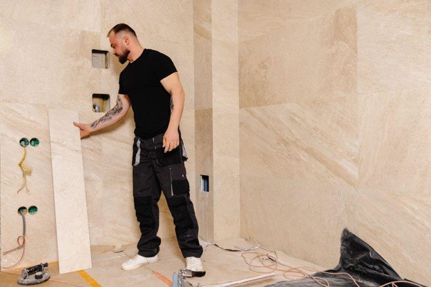 Bathroom remodeling contractor installing large-format wall tile during a residential bathroom renovation.