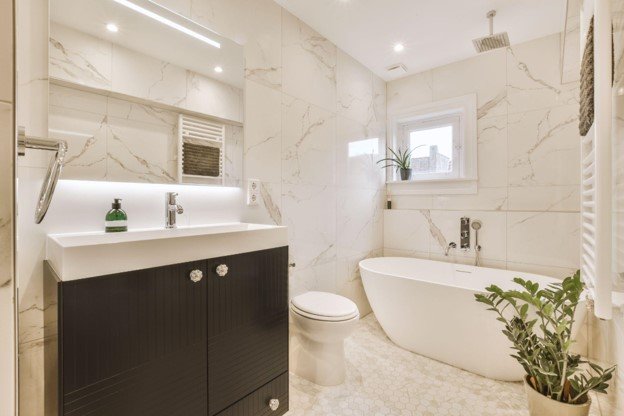 Completed bathroom remodel featuring a modern vanity, freestanding bathtub, toilet, tile, and updated fixtures.