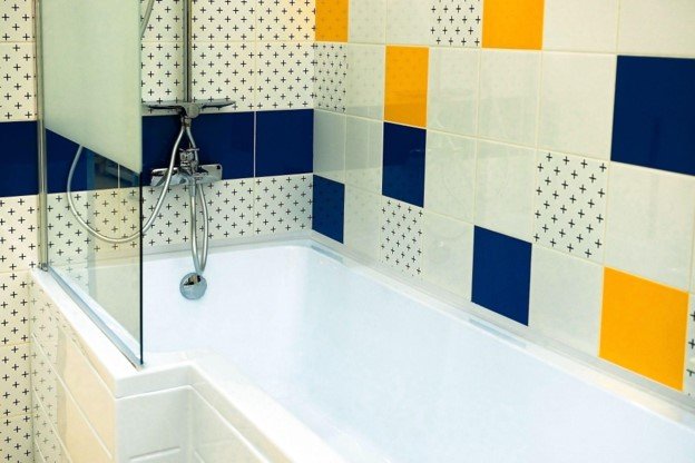 Completed bathtub and shower replacement with a white tub, glass shower screen, and decorative wall tile.