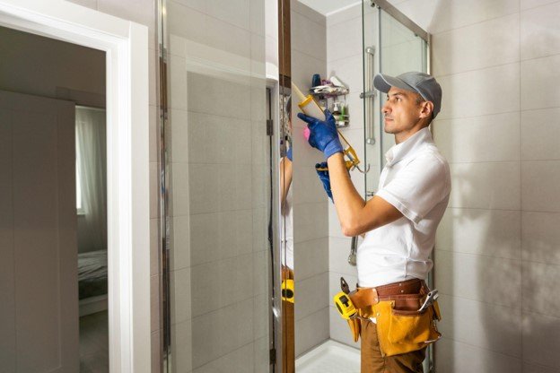 Bathroom remodeling work in progress with a contractor preparing materials inside a tiled bathroom.
